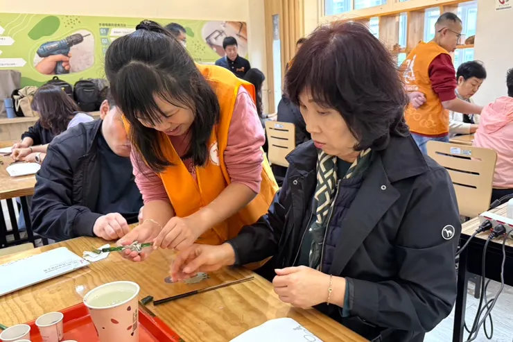 （圖說：在新北市政府社會局委託伊甸基金會辦理樹林彭福小作所的服務使用者(左)的帶領下，韓國貴賓體驗漆筷創作的樂趣。）