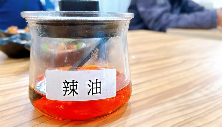 將小白拉麵特製辣油滴入蒜味豚骨拉麵中，紅艷色澤引人食慾，展現一碗多吃的豐富層次變化。