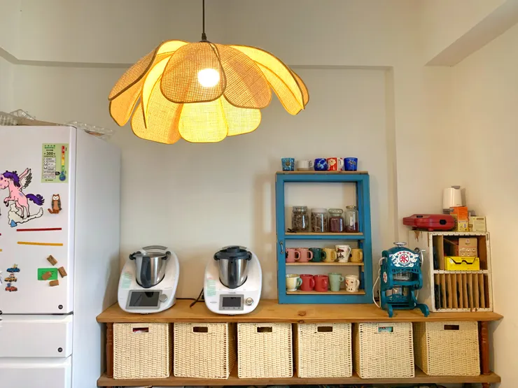 先生將不用的窗框改造成餐具層架，一致風格的收納藤籃呼應天花板上的小燈，讓空間增添溫度。因應小家庭選擇四人座木質小餐桌，使餐廳空間更加寬敞。