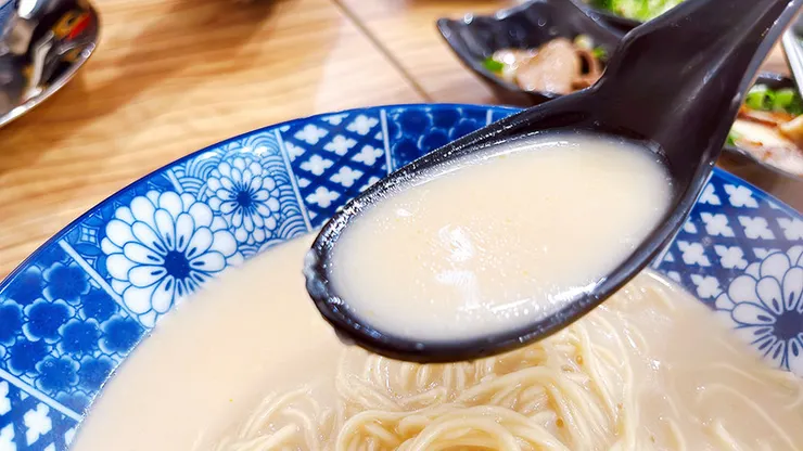 小白拉麵招牌蒜味豚骨拉麵特寫，濃郁白湯搭配大片炙燒叉燒與溏心蛋，視覺澎湃誘人。