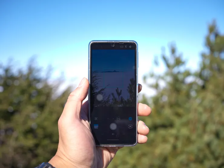 遠方是浮在雲海上的新康山,仔細看畫面左邊我的拇指附近,那個白色的點就是可以任意移動位置的「浮動式快門」,有感提升了拍照的便利性。
