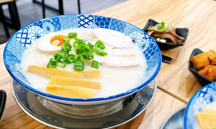 小白拉麵雞豚白湯拉麵俯視特寫，乳白色濃郁湯頭搭配舒肥雞肉、溏心蛋與木耳，視覺豐富澎湃。