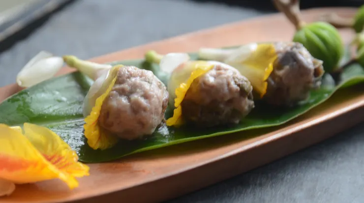 以月桃花為容器，把煙燻月桃肉丸子置入月桃花裡，可連同鮮花一起吃。