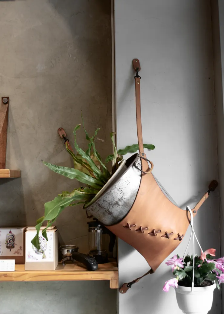 ▲林彥村利用皮革製作吊帶，點綴店內的植栽。呂國維攝。