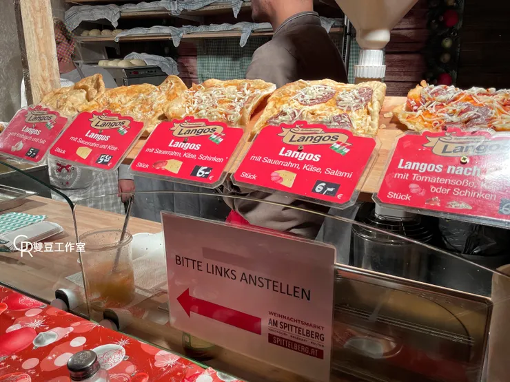 這攤是茶店老闆推薦的Langos~後面那堆生麵團加上前面配料就是讓人想吃，有實體可以手指點餐好貼心2022年每個調漲0.5歐