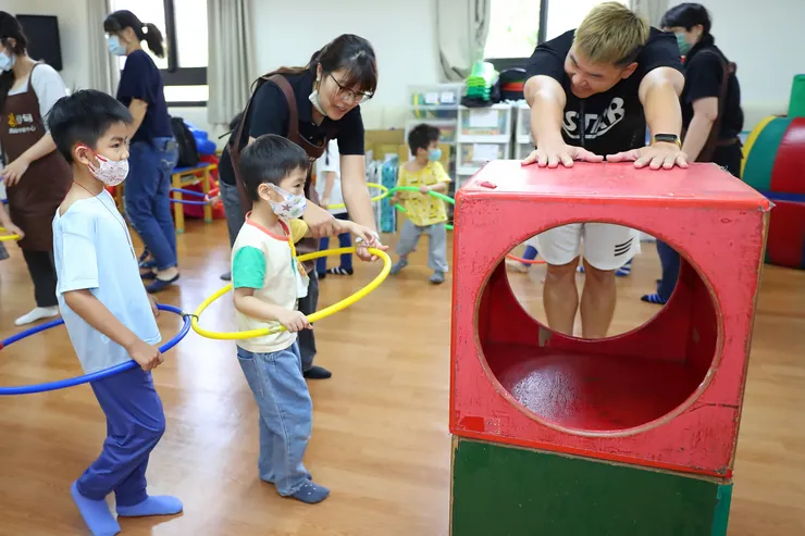 （圖說：皓皓(中)在教保員與大熊老師(右一)引導下，進行體能活動，培養身體協調與動作能力。）