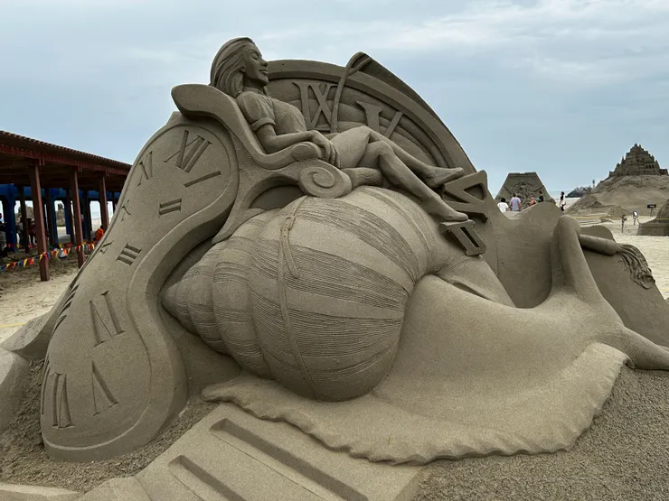 一位女少坐在蝸牛上，悠閒的表情，身後包圍著時鐘，告訴大家放慢腳步，越慢越美麗。