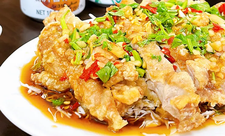 椒麻雞的微距特寫，展示炸雞腿肉的厚度與飽滿肉汁，麵衣金黃誘人。