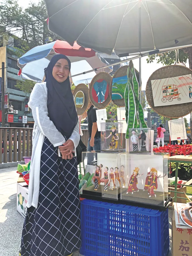 ▲印尼來台看護工 Pindy Windy 說，有一次在醫院進行看護工作的時候，隔壁病房的親友恰好是捏麵人師傅，教會她如何捏麵人。她對這樣手藝十分喜愛，寧願少睡一點覺，也要多捏幾個麵人兒。後面的《手推行動圖書館》畫作也是她的作品，她希望大家少滑一點手機，多享受閱讀的美好。（陳秋華  攝影）