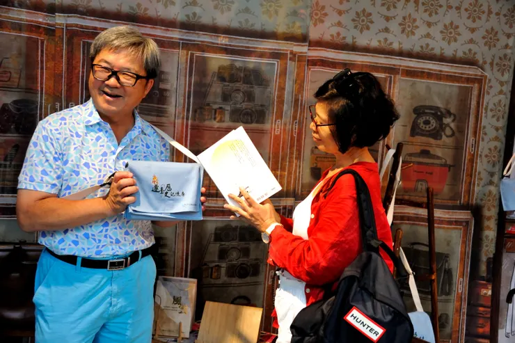 【裕釗、明珠伉儷購買展場紀念品與出版物後合影,明珠說要這樣才自然。】