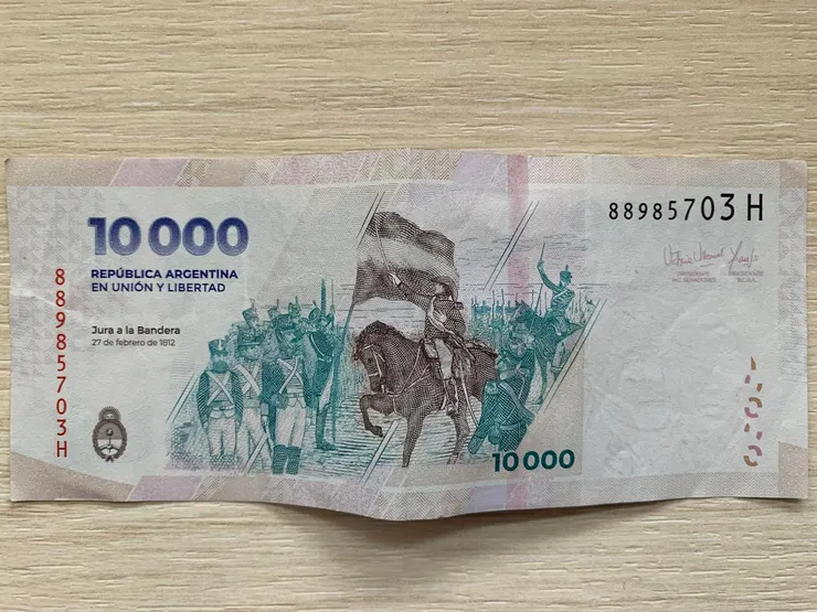 2024年新發行的阿根廷10,000披索紙鈔，折合已不到10美元。背面主圖是開啟阿根廷獨立戰爭的名畫《向國旗誓師》