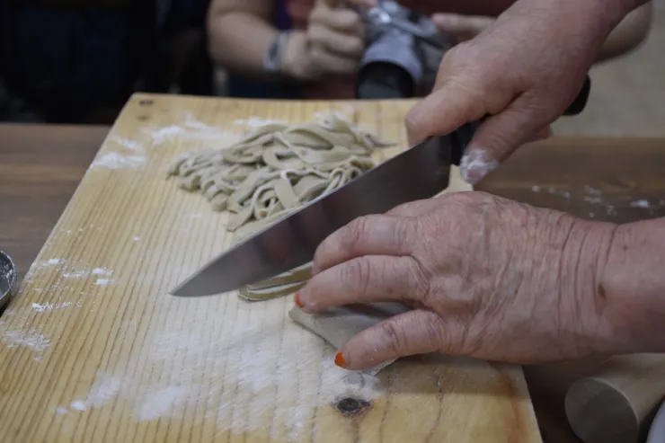 經過擀麵、摺疊、刀切，麵糰變成麵條，過程中會多次撒上麵粉避免沾黏。