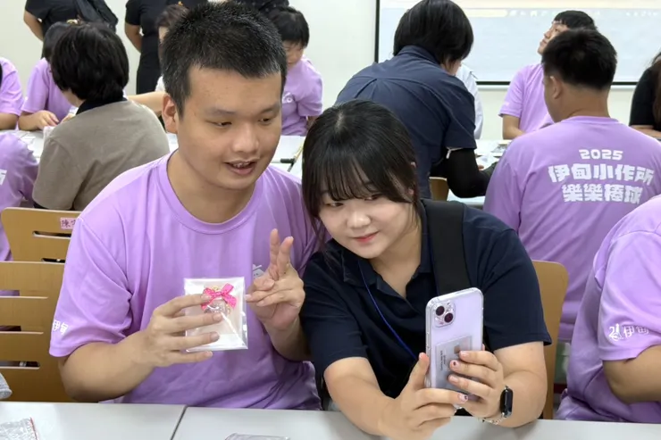 （圖說：韓國身心障礙者家庭協會的貴賓(右)與新北市政府社會局補助伊甸基金會辦理大同小作所的學員，共同完成「花漾球鑰匙圈」後，開心合影。）