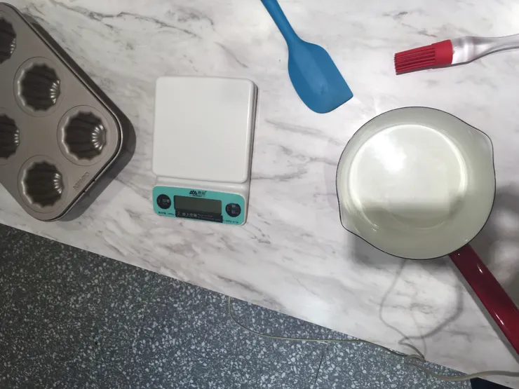 工具由左而右：可麗露模具、量器、刮刀、刷具、煮奶鍋