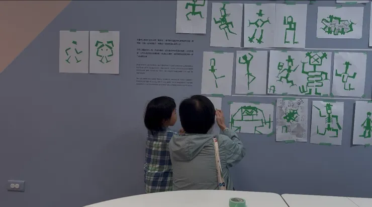 妳溫柔守護的背影,陪著孩子把作品貼在牆上。