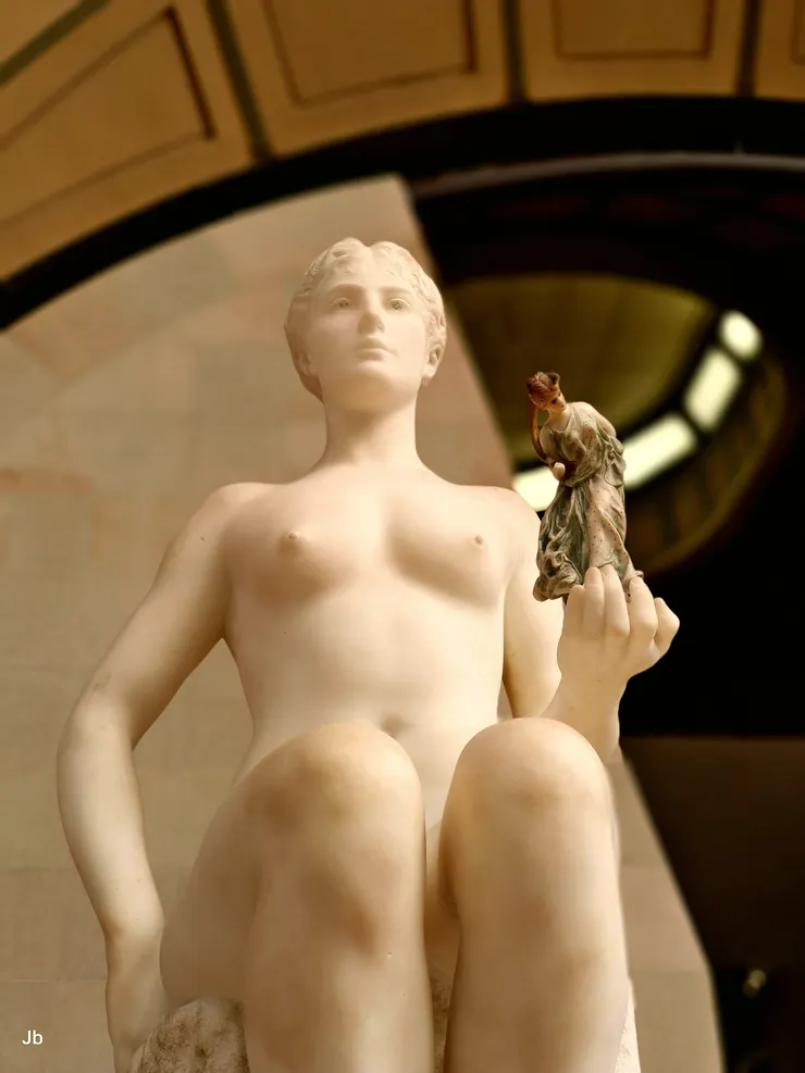 【法國藝術家 讓-里奧·傑洛姆（Jean-Léon Gérôme） 於1890年創作的《塔納格拉》（Tanagra），她是古希臘維奧蒂亞（Boeotia）地區一座以生產精美赤陶塑像聞名城鎮的擬人化，左手拿著象徵該地區出土的著名「塔納格拉小塑像」，這件作品不僅是對古典美學的致敬，也反映了19世紀末考古發現對藝術界的影響。】