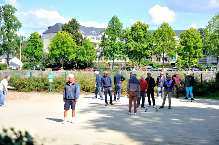 【教堂旁的公園空地上，一群老人在玩法式滾球。】