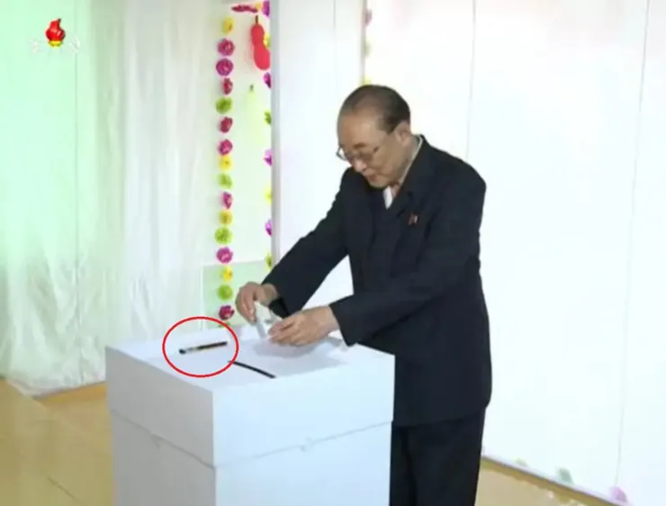 北韓選民在投票室投票，投票箱上放置原子筆（紅色圓圈）。〈朝鮮中央電視台，2015年畫面〉