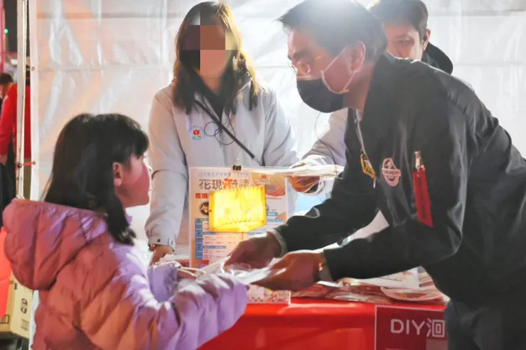 花蓮縣府代表與工作人員親手將限量的「翻閱奇蹟」書燈發放給排隊小朋友，傳遞溫馨佳節祝福。圖/花蓮縣政府提供