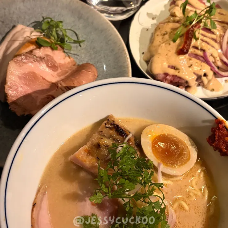 堅果南瓜雞白湯拉麵搭配香菜、火腿與溏心蛋，旁附胡麻牛肉小菜、舒肥雞胸與鴨胸叉燒拼盤，完整呈現雞白湯拉麵套餐內容