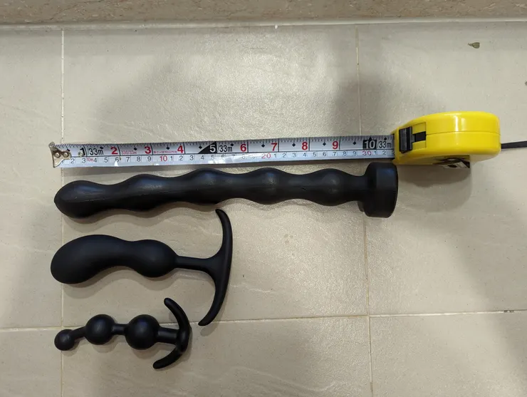 這是幾個我自己的肛塞。每一個的基底都是安全設計不會掉在肛門裡面取不出來。專門拿來調教乙狀結腸的就是最上面長的那隻，每一節的膨大處直徑最大3.5cm。PVC 的偏軟材質，軟硬度來說的話，把他的底部立起來的話，頭端會自己垂到地上。另外兩個葫蘆狀的短肛塞主要是調教前列腺的。