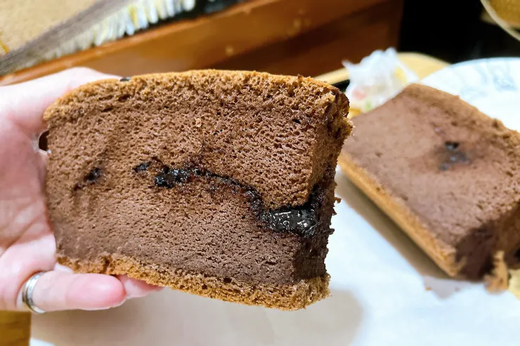 初蛋糕限量巧克力口味的斷面特寫，中間層夾著半熔融狀態的巧克力夾心，呈現如熔岩般的爆漿效果，