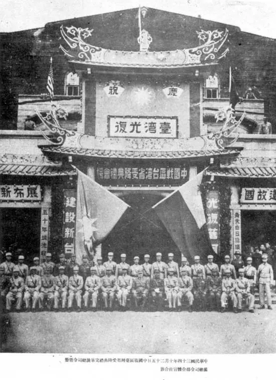 1945年10月25日,臺北公會堂舉行「中國戰區臺灣省受降典禮」後,臺灣省警備總司令部全體官兵合影。左半邊掛中國國民黨黨旗,右半邊掛中華民國國旗。Howard61313 at Chinese Wikipedia., Public domain, via Wikimedia Commons