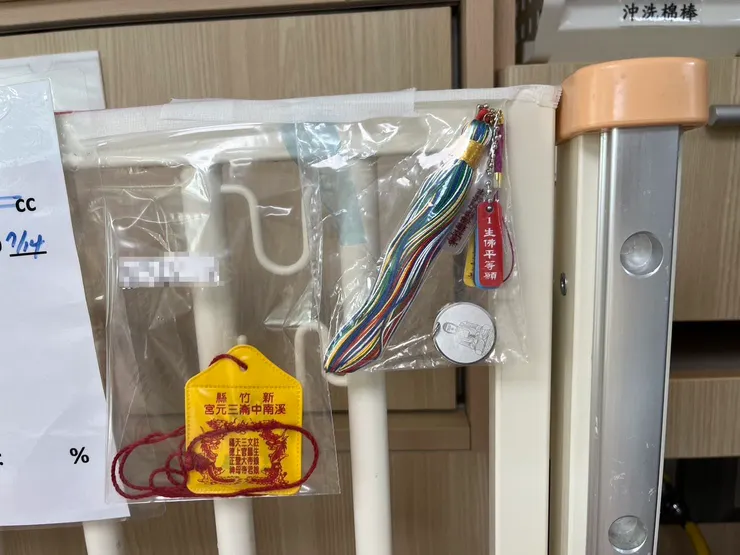 病床上貼著親友求來的平安符,有佛教的觀世音菩薩、藥師佛,有道教的三官大帝,再加上台北馬偕醫院的耶穌基督,祈求在眾神的護佑下,孩子能順利度過難關。