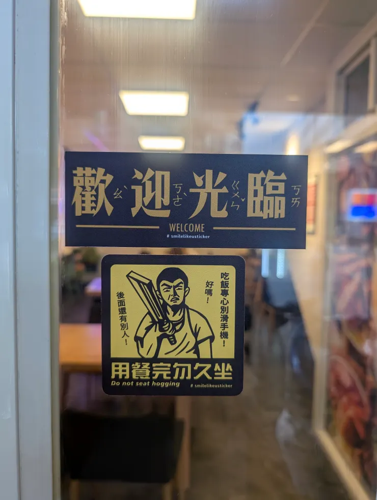 內用區玻璃門貼著歡迎光臨（澳客滾開）