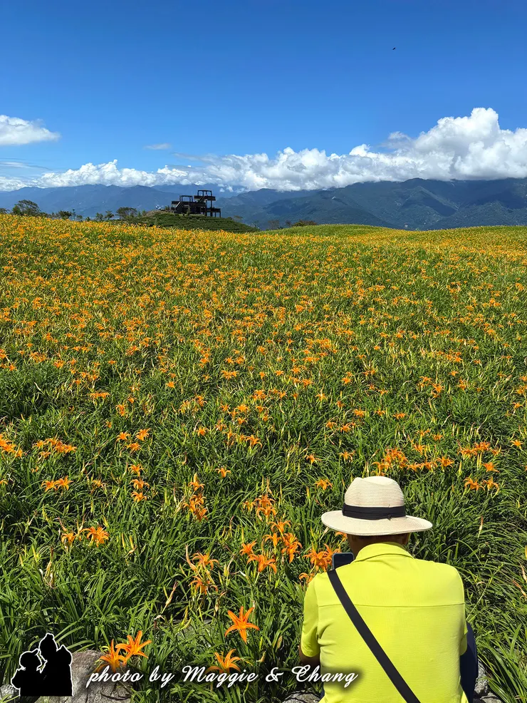 有人手持相機捕捉風景，畫面中可見攝影者姿態，增添旅遊或攝影的互動感。