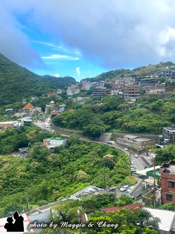 九份的山城魅力 ✨ 層層疊疊的房屋依山而建，像是拼貼出的立體畫作。蜿蜒的道路隨著山勢盤旋，綠意盎然的山谷與雲霧中的藍天相互交織，讓人忍不住停下腳步，好好欣賞這份專屬於九份的詩意。