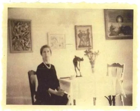 海倫偽裝成她的祖母約瑟芬・耶格斯，在假畫前擺姿勢，其中包括右側的一幅恩斯特森林畫作。