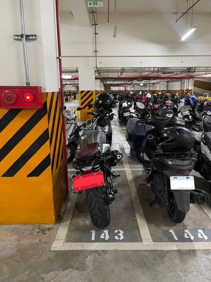 車長數據為「2.1公尺」的水平對臥重機BMW R nineT，合法停放私有機車停車場的狀態，和旁邊的YAMAHA勁戰幾乎沒有差別，後輪一樣沒有超線。非柏油路並沒有強制規定重機一定要停汽車格，各停車場可自行決定。