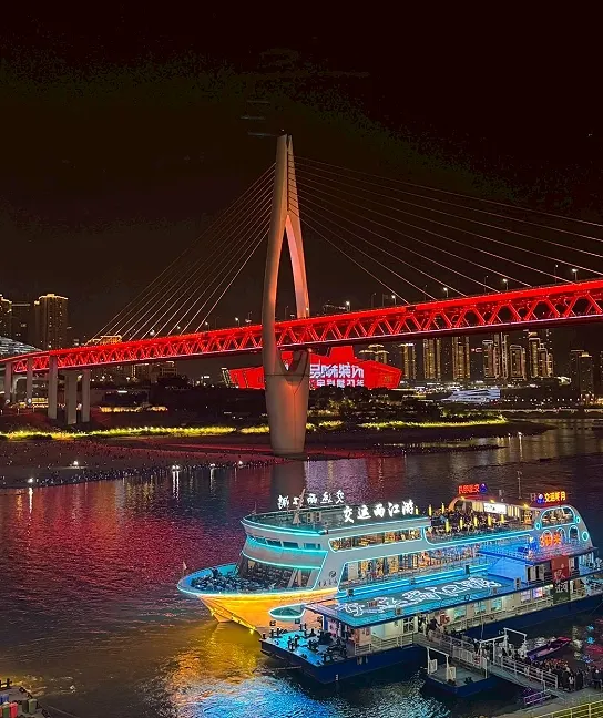 夜晚時分，洪崖洞對面的橋樑打燈配上光彩奪目的遊船，氣氛熱鬧