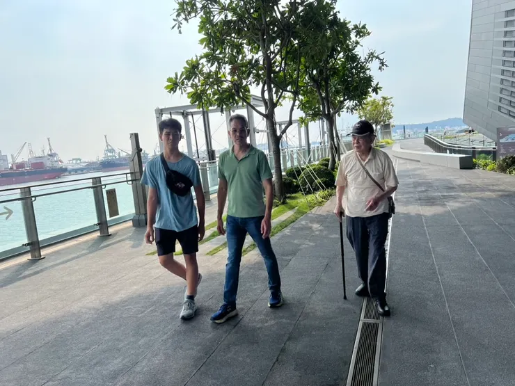 姪兒、弟弟、和爸爸走在旅運中心的平台，能看到高雄港灣和許多新穎的建築
