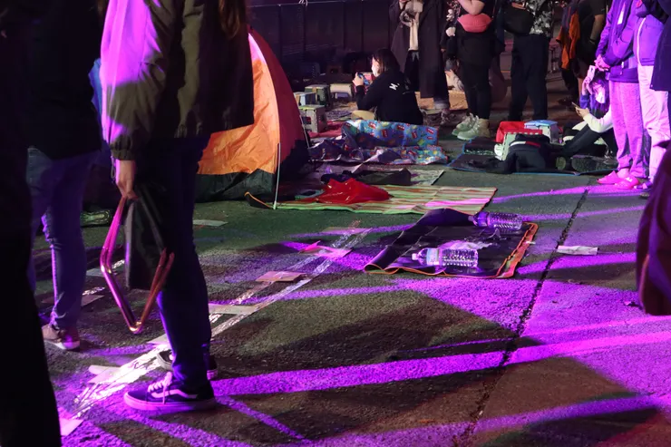 在地上綿延的地墊、板凳及行李