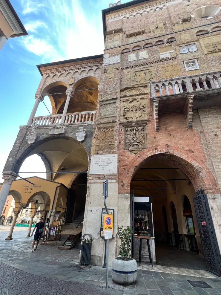 左上角看起來有兩個弧形窗，是Loggetta del Pandi 公告陽台 重要事件的公告、死刑判決、公社的決定、戰事，都是在公告陽台發布的。 這是在理性宮的西牆上。 帕多瓦人民在十四世紀時由這個陽台上聽見了與威尼斯的講和、當時統治者Francesco il Vecchio宣布退位與其後的世代更移  一個見證Padua歷史的街角