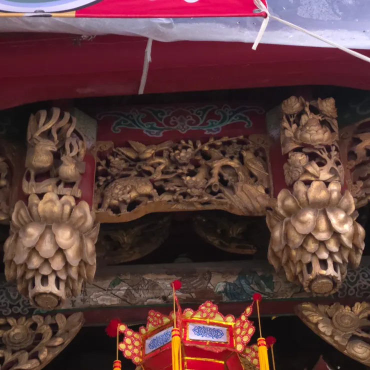 吊筒（垂花）與花籃造型 圖中左右兩側懸垂而下的金色圓柱狀雕刻。花鳥透雕工藝（鏤空雕）