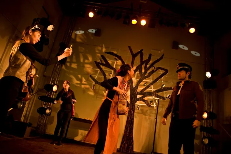 ▲遭逢環保人士的母親,被要求拍攝受害人假影片,後方愛好靈修的法國人不滿的看著這一切。本劇凡外國人一律都是用怪腔怪調的答錄機中文說話,墨西哥人是標準國語,希望顛覆英語作為正統一事,是以這齣戲只能在中文語境發生,用中文諧擬外國話。如果可以用英文拍《末代皇帝》,那為什麼不能用中文寫外國的故事?(由左至右:朱家儀、朱育宏)