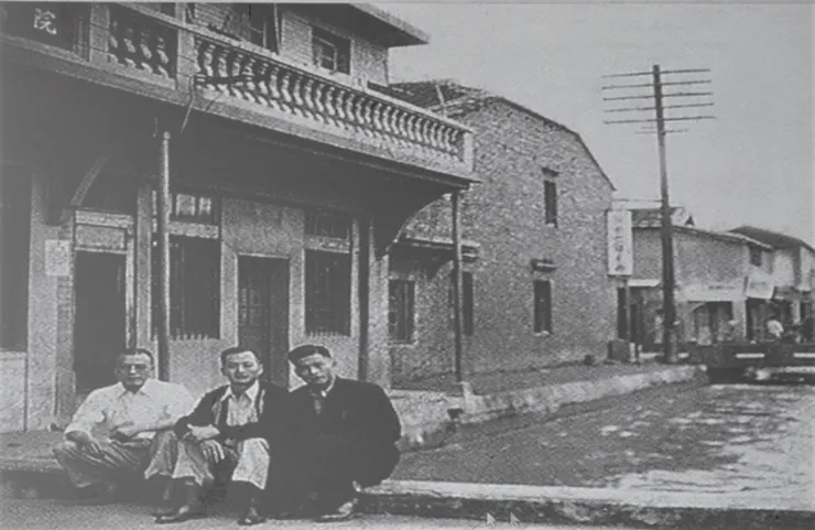 景文街舊照，道路東側是瑠公圳。三位醫師座在診所前的便橋上拍照