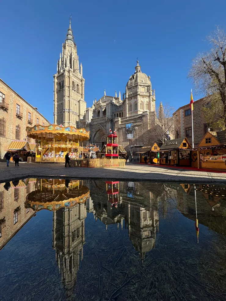倒映著晴朗天氣下的教堂與聖誕市集的水池