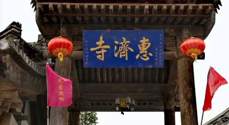 慧濟寺的正門上掛著藍色的匾額，上面書寫著「惠慈寺」字樣，兩側紅燈籠掛在門柱上，增添了幾分莊嚴與神聖。