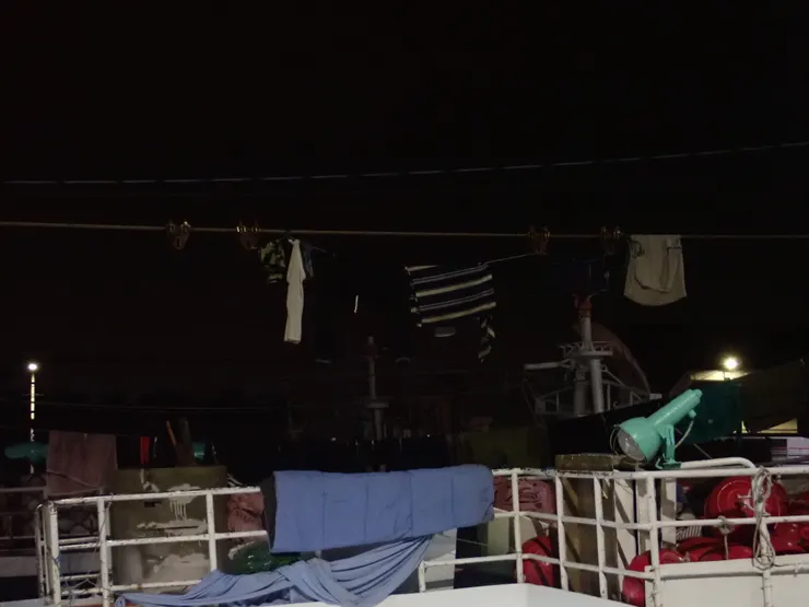 船艙是黑的,桅杆間拉起的曬衣繩掛著衣物,像幾面垂危的旗幟;再走近,甲板上立著魚桿,紅色的浮球零散的滾落在地。(攝於生鮮魚市場)