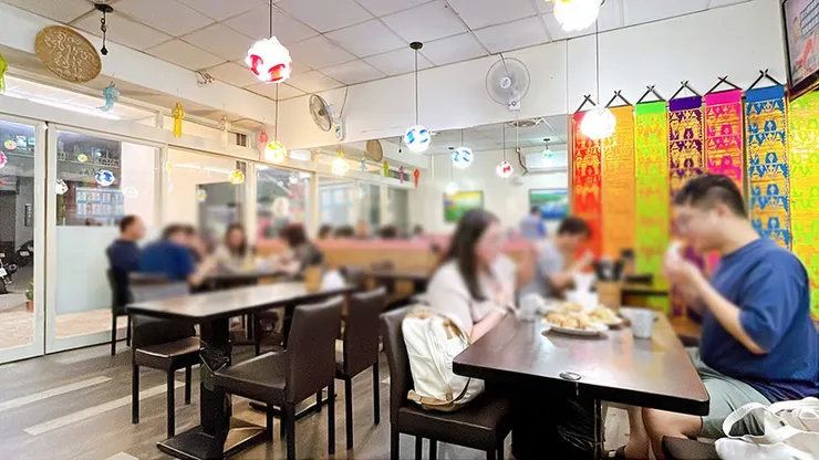 夏天小館泰式料理內部裝飾，牆上掛著泰國傳統刺繡織品與用餐客人側拍。