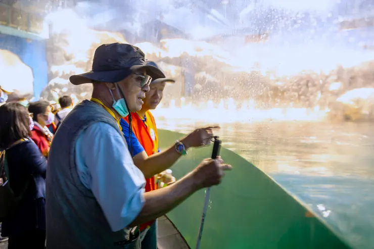 （圖說：蘇相淋大哥(前)在志工何光耀的口述下，用「心」感受極地水域中的動物生態。）