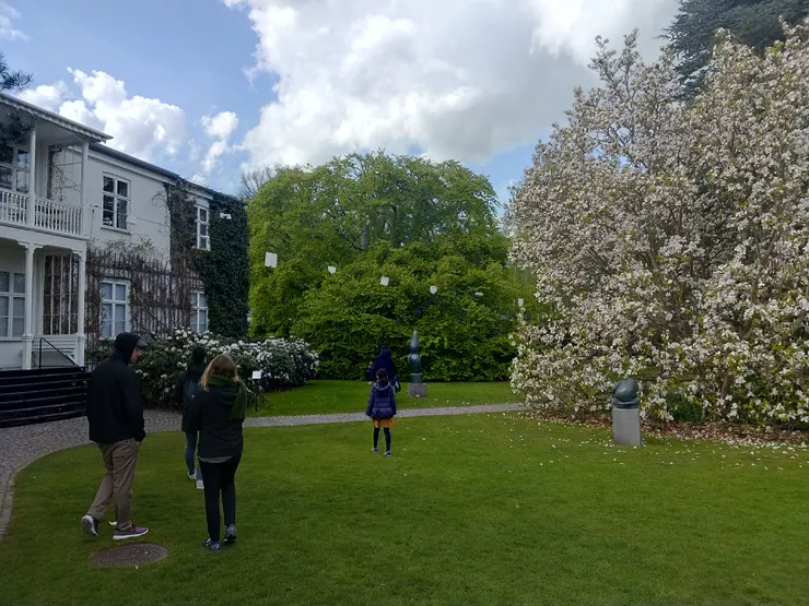 入口處的草坪、戶外藝術、樹，形成一幅美景