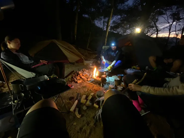 夕陽下，營火前、等著上菜的人們。