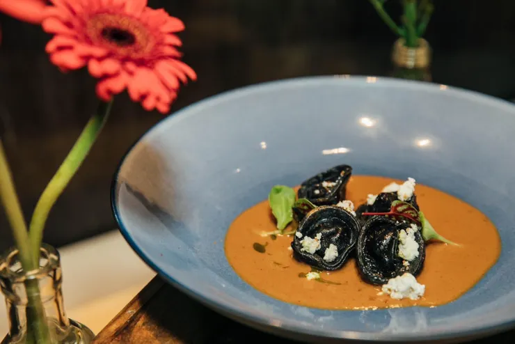 江懿軒製作的手工墨魚帽餃，選用彌陀生態蝦，搭配鱈魚洋芋泥、高雄烏魚子、檸香瑞克塔，並澆上熬煮的奶油生態蝦殼汁。（照片提供／江懿軒）