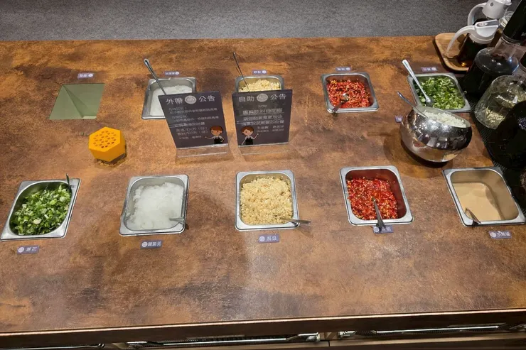 自助醬料區。蔥花、沙茶、蒜頭、蘿蔔泥、小米辣、胡麻醬，想調重口味或清爽派都能自己搭。