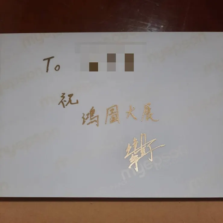 這是簽名賀卡照片的背面，金色簽名筆很閃亮